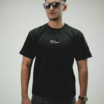 Man wearing black terry fabric drop shoulder t-Shirt with round neck, styled with dark denim jeans