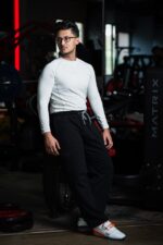 Man wearing white compression t-shirt training with a medicine ball at the gym